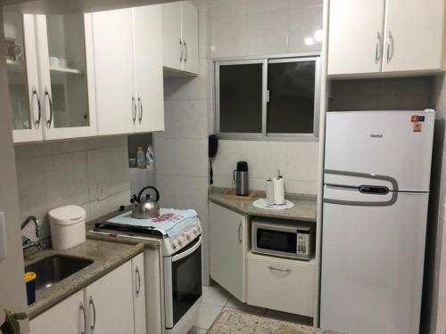 cocina con armarios blancos y nevera blanca en Apto aconchegante 100m Shopping Beiramar en Florianópolis