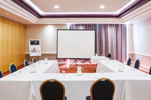 a conference room with white tables and chairs and a screen at Mercure St Helens in Saint Helens