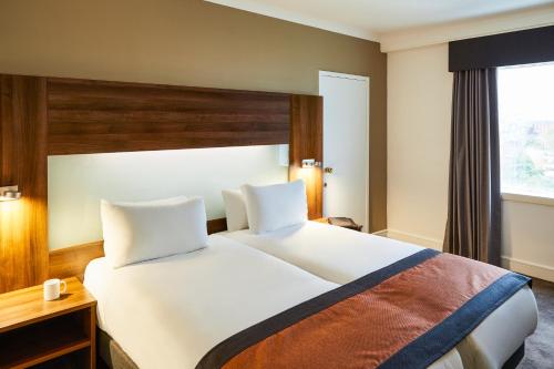 a bedroom with a large white bed and a window at Mercure St Helens in Saint Helens