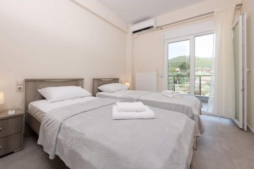 two beds in a white room with a window at Villa Venetta in Skala Rachoniou
