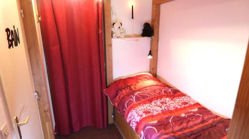 a small bedroom with a bed and a red curtain at Mon Mounier : Studio cosy au pied des pistes / Vue de rêve ! in Beuil