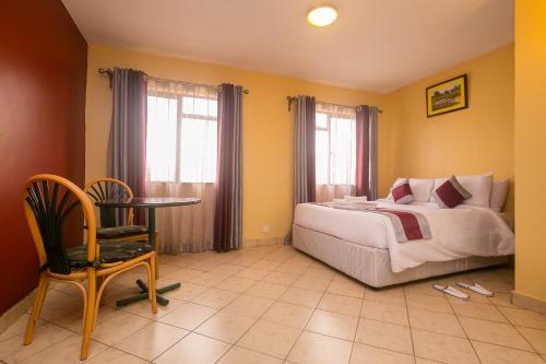 Plus254 Hotel في نيروبي: غرفة نوم بسرير وطاولة وكرسي
