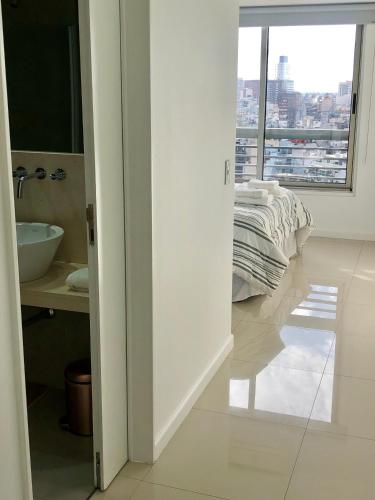 a white bathroom with a bed and a window at Topacio Tower apartamento de lujo in Buenos Aires