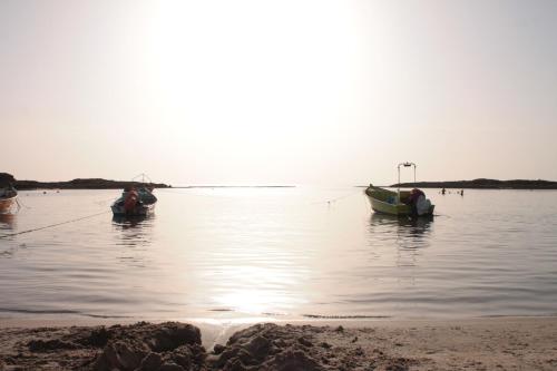 two boats sitting in the water on a beach at Dor village in Dor