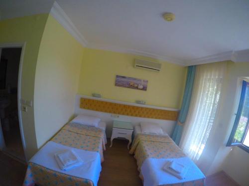 a small room with two beds and a window at İlkiz Beach Hotel in Oludeniz