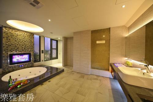 a bathroom with a tub and a sink and a tv at Doule Motel in Taichung