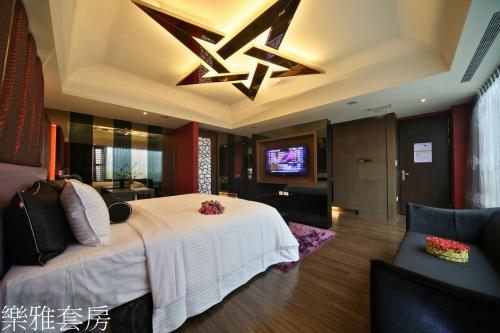 a bedroom with a white bed and a television at Doule Motel in Taichung