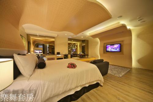 a bedroom with a large white bed and a tv at Doule Motel in Taichung