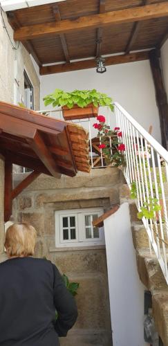 a person sitting on the stairs of a building with plants at A Casinha do Beco in Gouveia