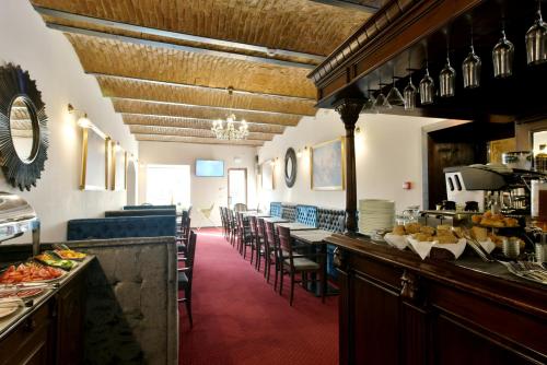 un ristorante con un lungo bar con tavoli e sedie di Safrano Palace a Braşov