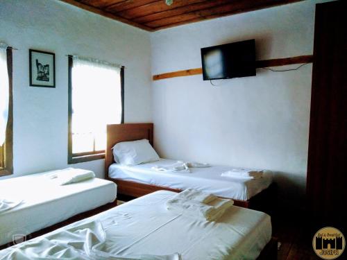 a room with two beds and a tv on the wall at Bed & Breakfast JOSIPH in Berat