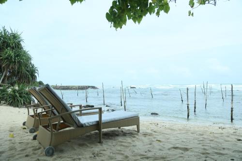 a beach chair sitting on the sand next to the water at Villa Koggala in Koggala