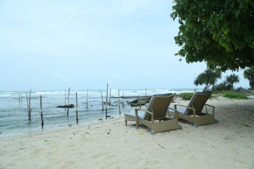 two chairs sitting on a beach near the water at Villa Koggala in Koggala