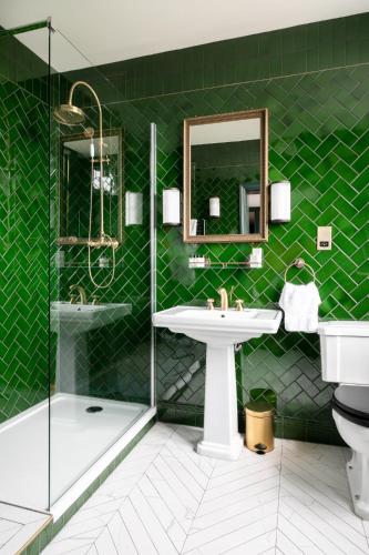 a green bathroom with a sink and a shower at The Bedford Balham - Live Music Venue in London