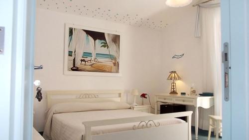 - une chambre blanche avec un lit et un bureau dans l'établissement La Rosada, à Giglio Porto