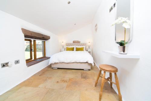 ein weißes Schlafzimmer mit einem Bett und einem Holzhocker in der Unterkunft The Nook Cottage in Carlisle