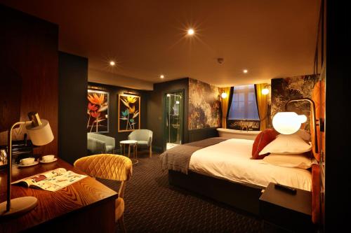 a hotel room with a bed, chair, and nightstand at The Bedford Balham in London