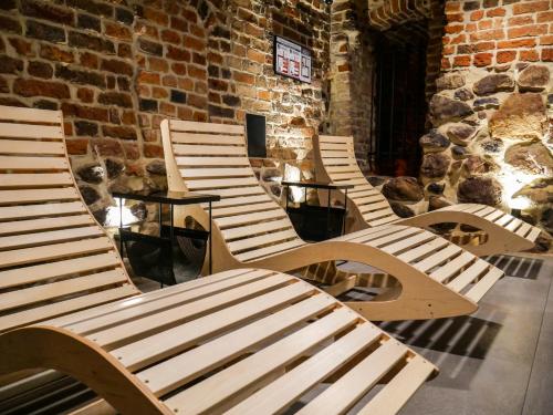 a row of wooden benches sitting in front of a brick wall at Hotel Spichrz in Toruń