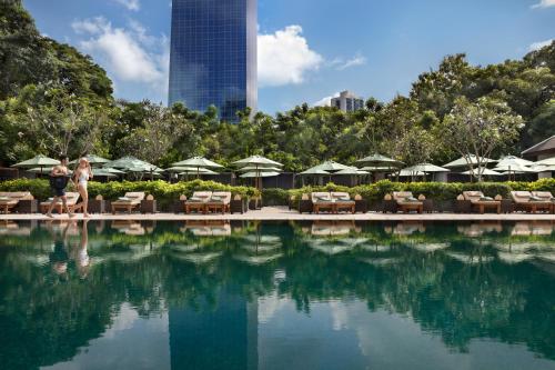 a pool with chairs and umbrellas in a resort at The Sukhothai Bangkok in Bangkok