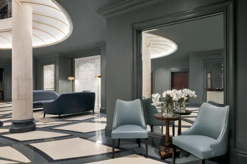 a lobby with chairs and a table and a mirror at Hotel Kämp in Helsinki
