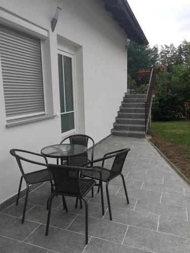 a patio with three chairs and a table and stairs at New apartment near Plitvice lakes in Smoljanac