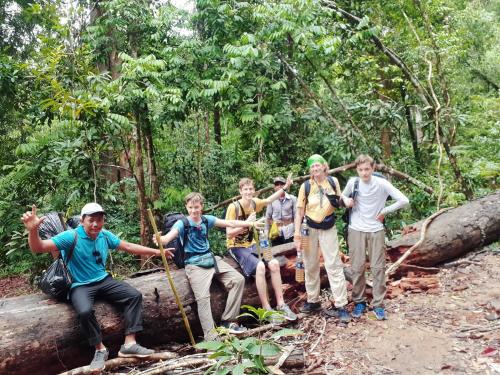 a group of people standing on a fallen tree in the forest at Tribal Village Homestay & Trekking in Banlung
