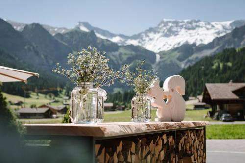 dois frascos de vidro com flores numa mesa com montanhas em Wildstrubel Lodge em Adelboden