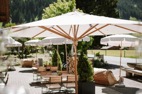 un grupo de mesas y sillas bajo una sombrilla en Wildstrubel Lodge en Adelboden