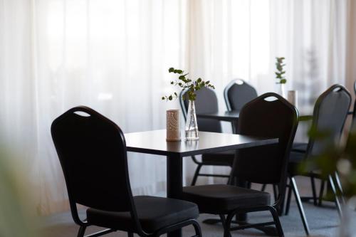 a dining room table with chairs and a vase of flowers on it at Quality Hotel Sundsvall in Sundsvall