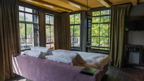 a large bed in a room with large windows at Hotel Frank since 1666 in Amsterdam
