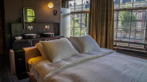 a bedroom with a bed and a large window at Hotel Frank since 1666 in Amsterdam