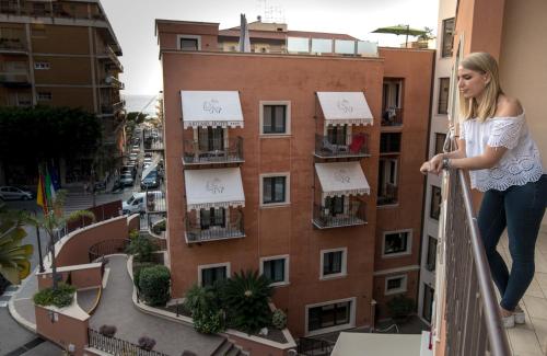 a woman standing on a balcony of a building at Artemis Hotel in Cefalù