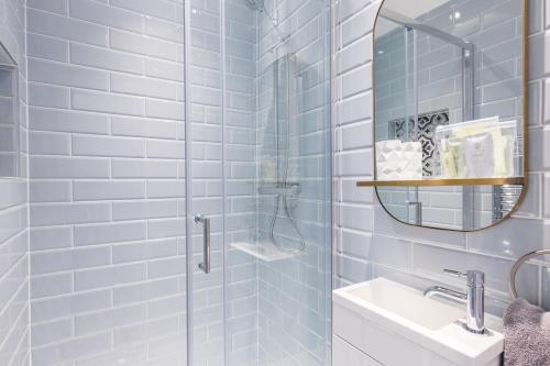 La salle de bains est pourvue d'une douche, d'un lavabo et d'un miroir. dans l'établissement BlueNess, City Centre Luxury Apartment, à Inverness