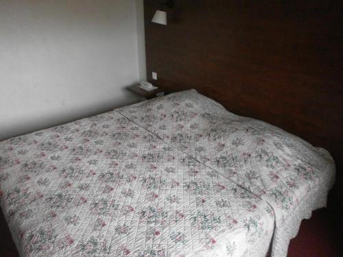 a bedroom with a bed with a floral bedspread at Hôtel Maya in Cavalaire-sur-Mer