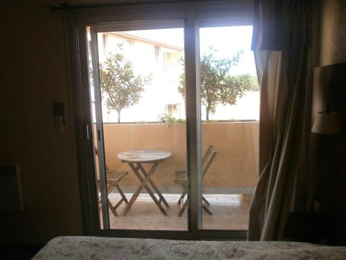 a room with a sliding glass door with a table outside at Hôtel Maya in Cavalaire-sur-Mer