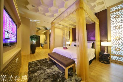 a bedroom with a canopy bed and a tv at Doule Motel in Taichung