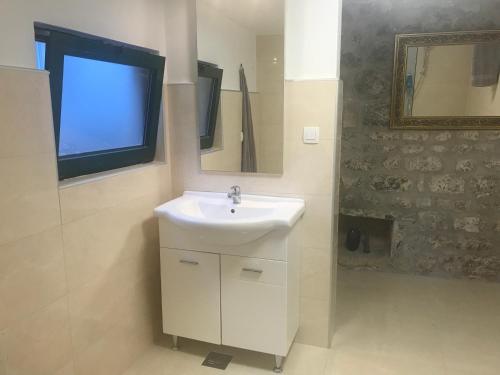 La salle de bains est pourvue d'un lavabo, d'un miroir et d'une télévision. dans l'établissement Bounty Apartments, à Šibenik