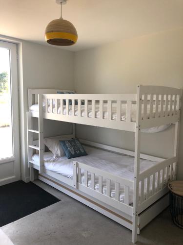 Ce lit se trouve dans un dortoir doté de 2 lits superposés blancs et d'une fenêtre. dans l'établissement Les Gîtes de la Clere, à Le Grand Vieil