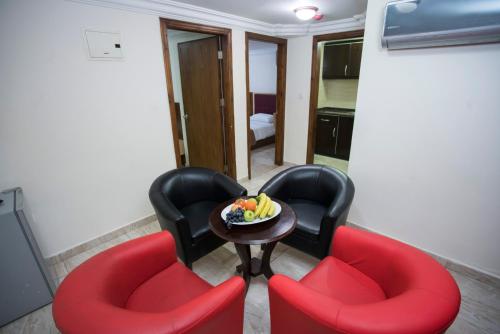 a room with two red chairs and a table with a bowl of fruit at The Yacht Hotel in Aqaba