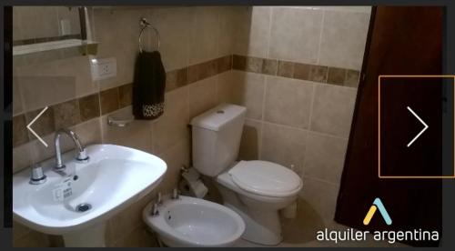 a bathroom with a white toilet and a sink at Cabañas Thijada in Mina Clavero
