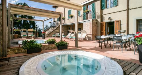 a hot tub on a patio with a table and chairs at Palazzo Leopoldo Dimora Storica & Spa in Radda in Chianti