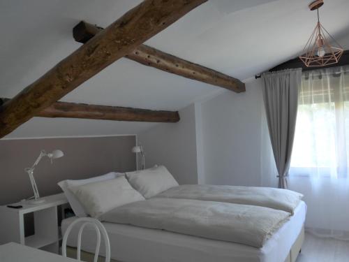 a white bedroom with a bed and a table at La Tana Rooms in Lenno