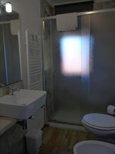 a bathroom with a shower and a sink and a toilet at La Tana Rooms in Lenno