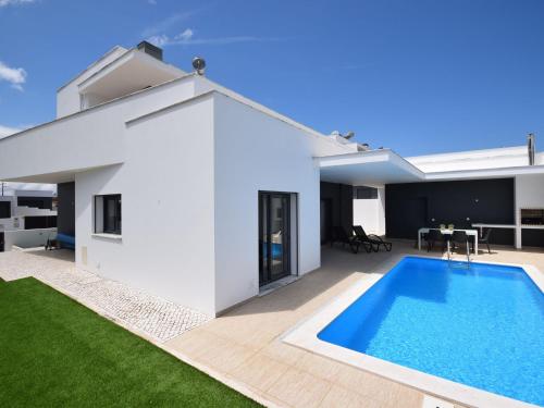 a white house with a swimming pool in the backyard at Modern villa with private pool near the beautiful beach of Foz de Arelho in Nadadouro