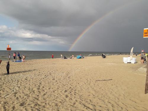 un grupo de personas en una playa con un arco iris en Apartament Nadmorski LUX1, en Sztutowo
