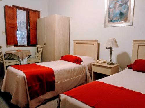 a hotel room with two beds with red sheets at Posada del Frayle Bentos in Fray Bentos