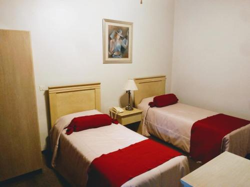 a hotel room with two beds with red and white sheets at Posada del Frayle Bentos in Fray Bentos