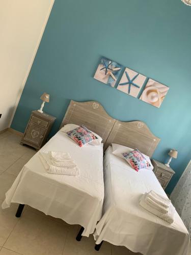 two beds in a room with a blue wall at Memmea's House in Specchiolla 