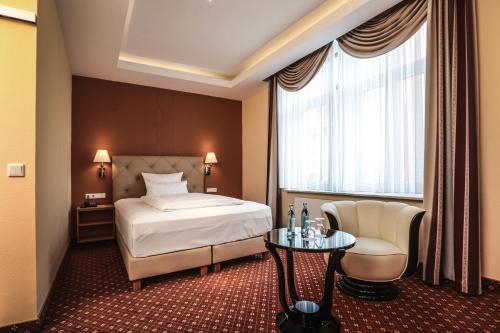 ein Hotelzimmer mit einem Bett und einem Stuhl in der Unterkunft Hotel Mack in Mannheim