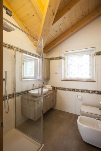 a bathroom with a glass shower and a sink at Fiemme Home Mountain Apartment in Tesero